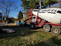 Cement mixer and small cart to transport batches to base form without truck needing to enter back yard during construction of dark green basketball court in Duxbury, MA.