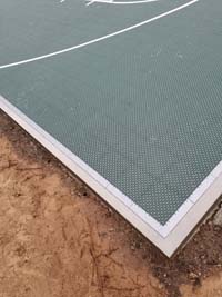 Corner detail of dark green backyard basketball court in Duxbury, MA.