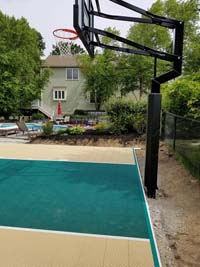 Sand and emerald green backyard basketball court in Easton, MA.