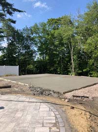 Freshly poured concrete base, waiting to dry, for what will become a blue and gray residential basketball court in Easton, MA.