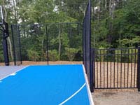 Highlighting right side and fance of blue and gray residential basketball court in Easton, MA.