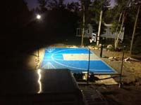 Overview of blue and gray basketball court under optional lighting system at night in Wareham, MA.