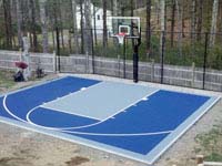 Navy and ice blue backyard basketball court with rebounder and goal system in Kingston, MA.