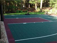Dark green and burgundy multicourt with basketball goal system and rebounderin Kingston, MA.