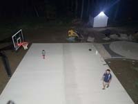 Partially complete basketball court featuring Celtics logo, with fire pit, patio, and light for night play, in Londonderry, NH.