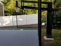 Side view of goal system and end of slate green and titanium silver/grey basketball court in Needham, MA.