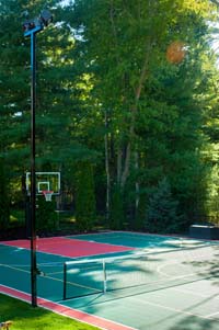 Large home basketball court with net for tennis or volleyball, in-ground trampolin, and lighting system in Pembroke, MA.