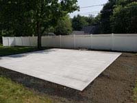 Concrete foundation ready for small slate green and titanium residential basketball court in Reading, MA.