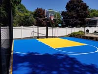 Custom royal blue and yellow backyard basketball court constructed in Stoneham, MA.
