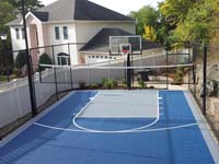 Blue and grey basketball court with optional net for other sports, making creative use of awkward yard space in Stoneham, MA.