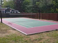 Red and green home court in Sudbury, MA, primarily lined for tennis and secondarily lined for basketball. Tennis net is adjustable and removable.
