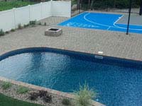 Light blue and grey basketball court integrated with pool deck in Wareham, MA, also featuring shuffleboard.