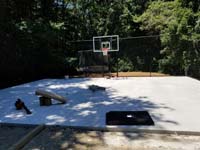 Concrete base is ready to lay low impact tile for black and grey home backyard basketball court in Wellesley, MA.